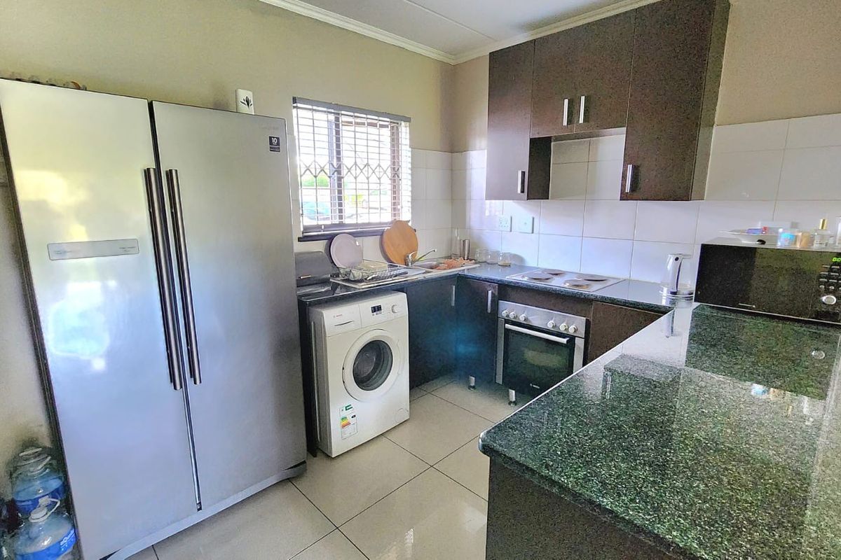 Functional kitchen featuring granite countertops, built-in oven, electric hob, tiled backsplash, and ample laminate cabinetry for storage.