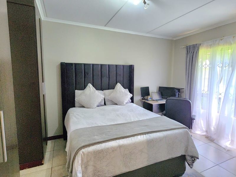 A well-maintained bedroom featuring tiled flooring, a built-in wardrobe, and neutral wall finishes with natural light from the window.