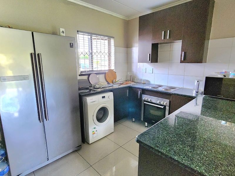Functional kitchen featuring granite countertops, built-in oven, electric hob, tiled backsplash, and ample laminate cabinetry for storage.