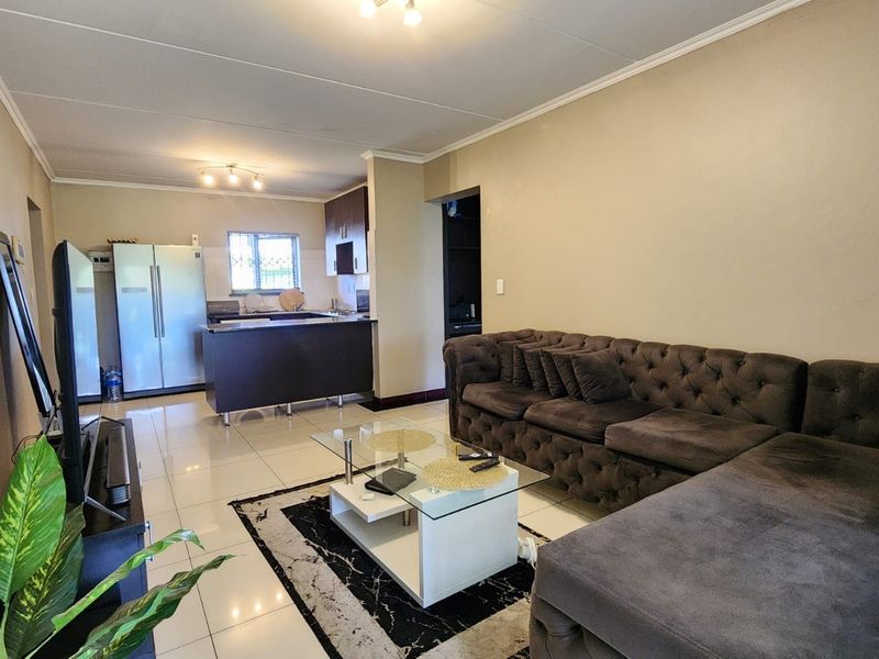 Open plan living area featuring tiled flooring and a functional kitchen with built-in cabinetry and a breakfast island.