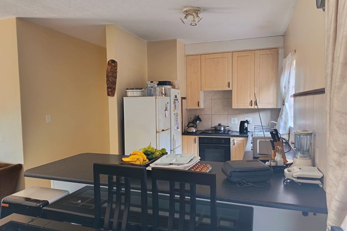 A functional kitchen featuring light wood cabinetry, a tiled backsplash, built-in oven and hob, and a convenient breakfast bar counter.