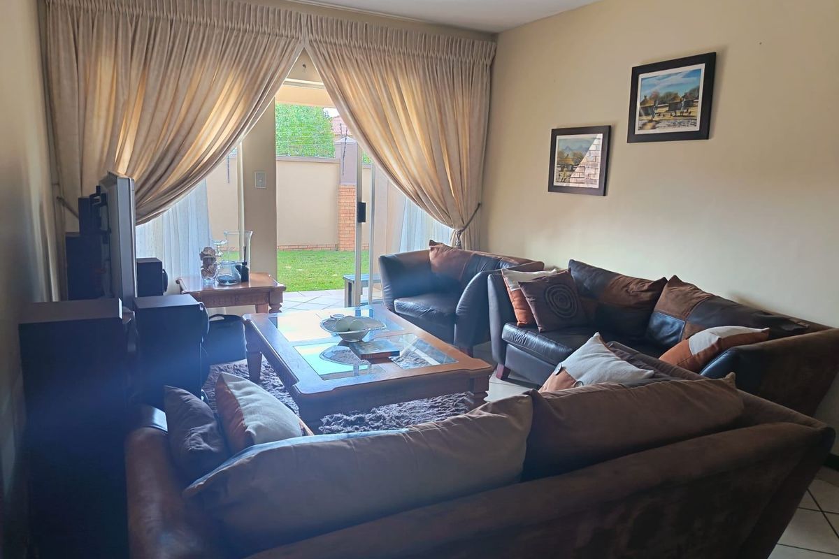 A comfortable living room featuring tiled flooring and a large sliding glass door that provides direct access to the rear patio and garden.