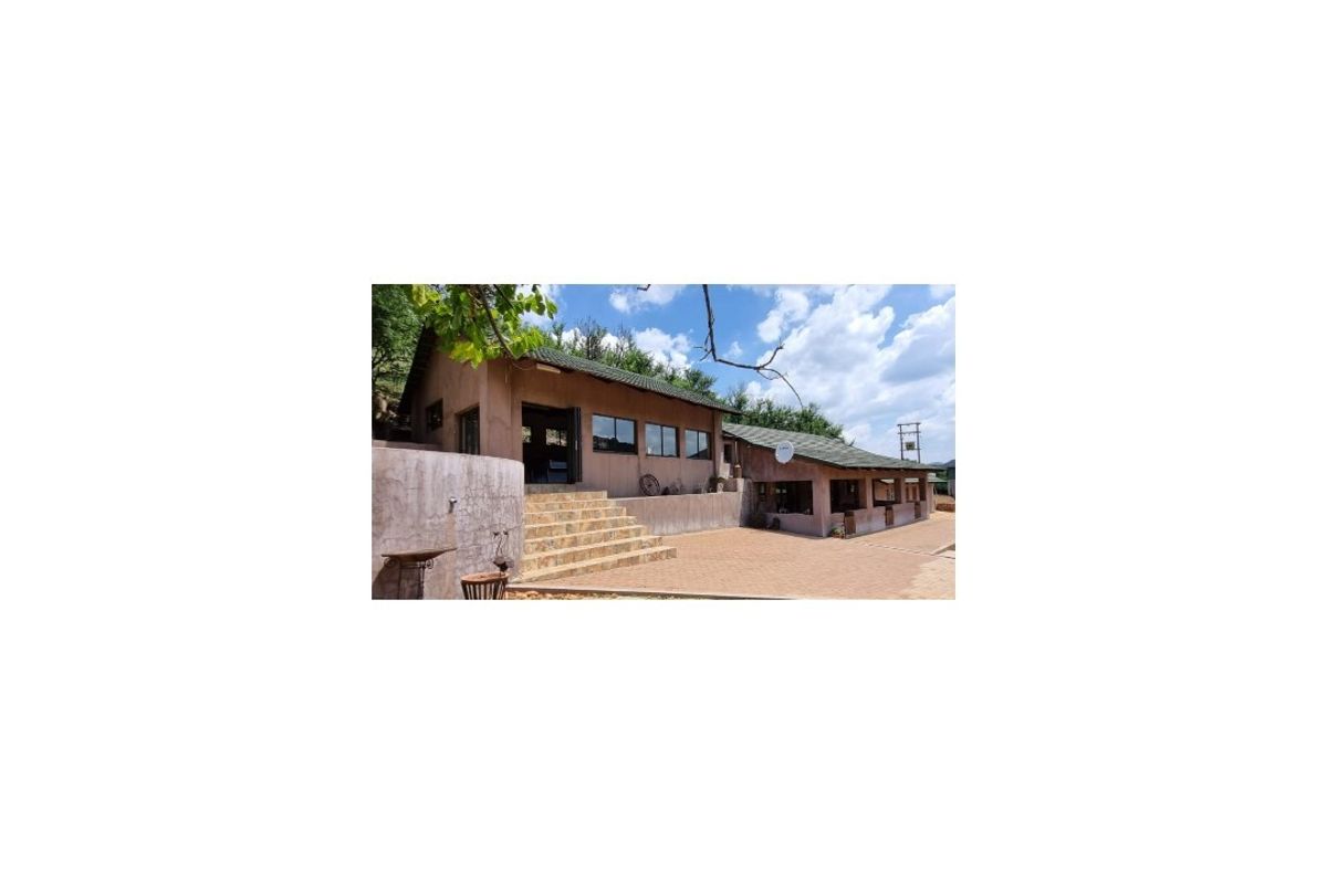 Rear exterior view of the farm building featuring a paved patio area, tiled steps, and a pitched roof structure.