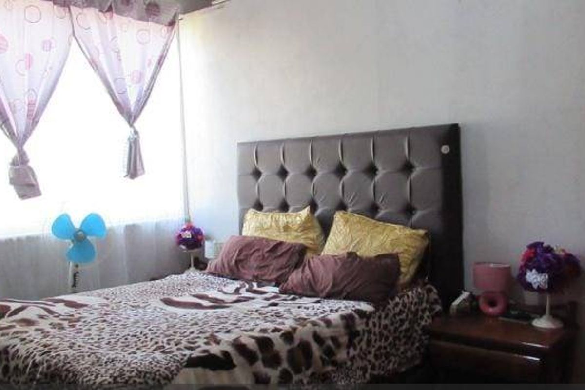 A standard bedroom featuring a window with curtains and neutral wall finishes, providing a functional sleeping space.