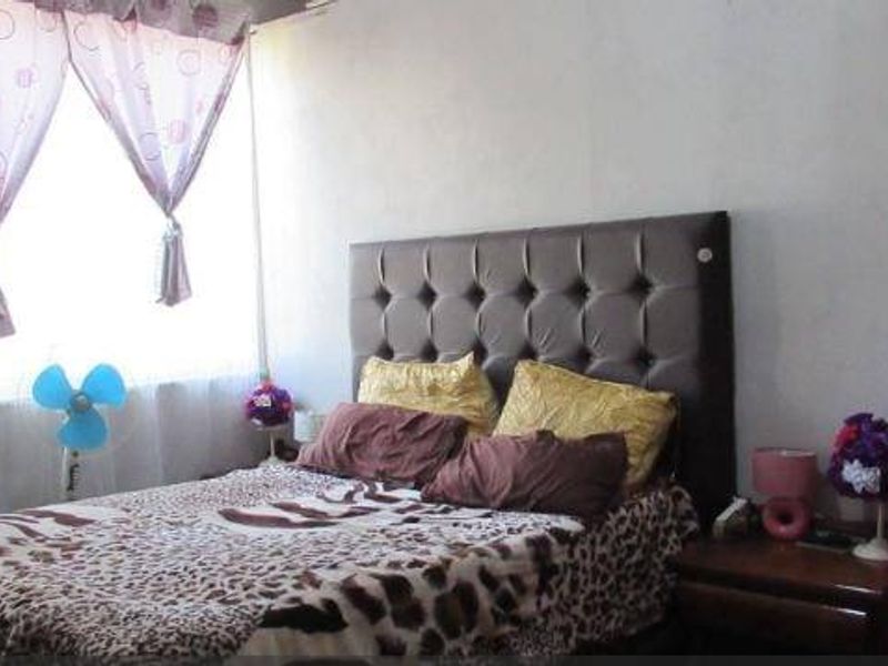 A standard bedroom featuring a window with curtains and neutral wall finishes, providing a functional sleeping space.