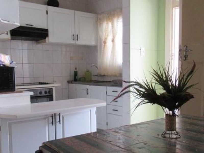 A compact kitchen featuring white cabinetry, a built-in oven and hob, and tiled backsplash, offering a functional layout with potential for modern updates.