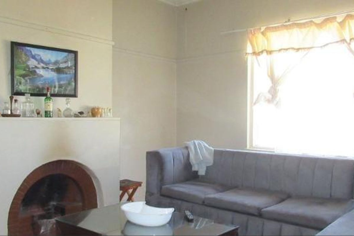 A living room featuring a traditional fireplace with a mantelpiece and a picture rail, offering a classic layout with natural light.
