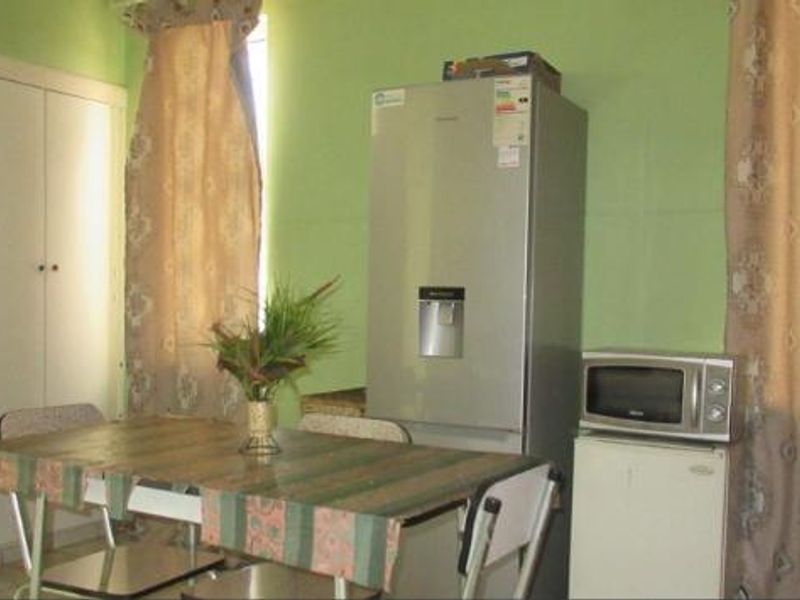 A functional kitchen area featuring a built-in storage cupboard and space for appliances, currently finished with bright green wall paint.