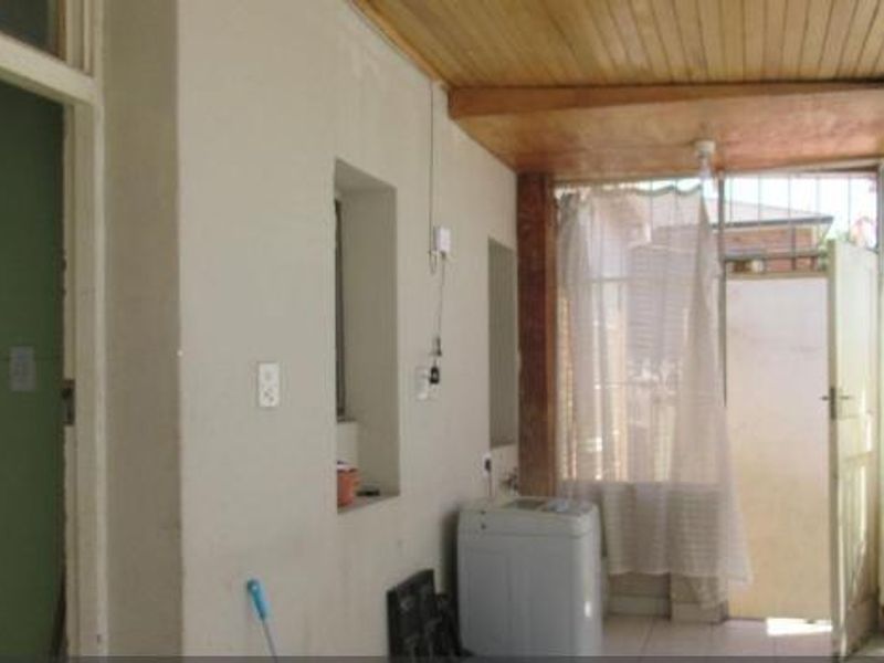 A covered outdoor patio area featuring a timber ceiling and tiled flooring, providing access to the rear of the property.
