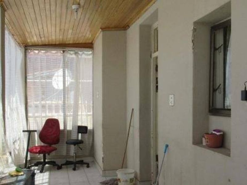 A covered patio or sunroom featuring a timber-clad ceiling, tiled flooring, and large windows, offering a versatile space for relaxation or additional living area.