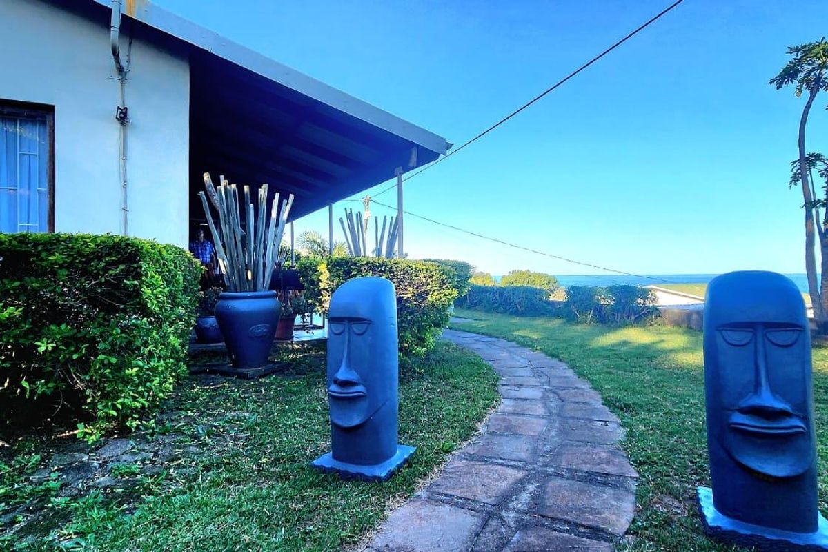 A rear garden view featuring a stone pathway leading to a covered patio area with a view of the surrounding landscape.