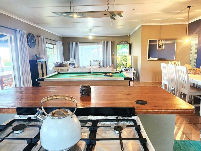 Spacious open-plan living area featuring a kitchen with a timber breakfast bar, flowing into a dining and entertainment space with sliding door access.