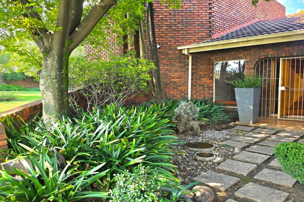 A well-maintained rear garden area featuring a brick facade, paved walkway, and established landscaping, providing a private outdoor space.