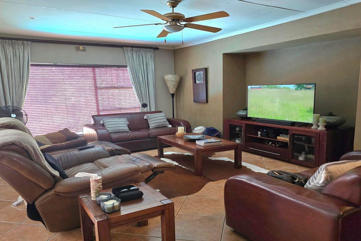 A spacious living room featuring tiled flooring, a ceiling fan, and a built-in wall niche for media storage.