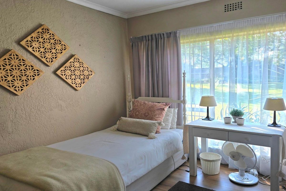 A cozy bedroom featuring textured walls, laminate flooring, and a large window that allows for ample natural light.