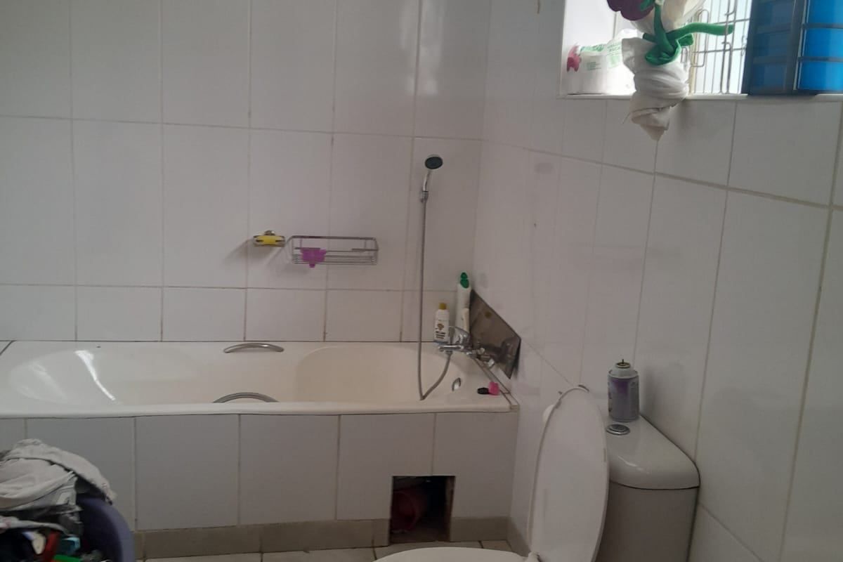 A functional bathroom featuring a built-in bathtub and toilet with white wall tiling throughout.