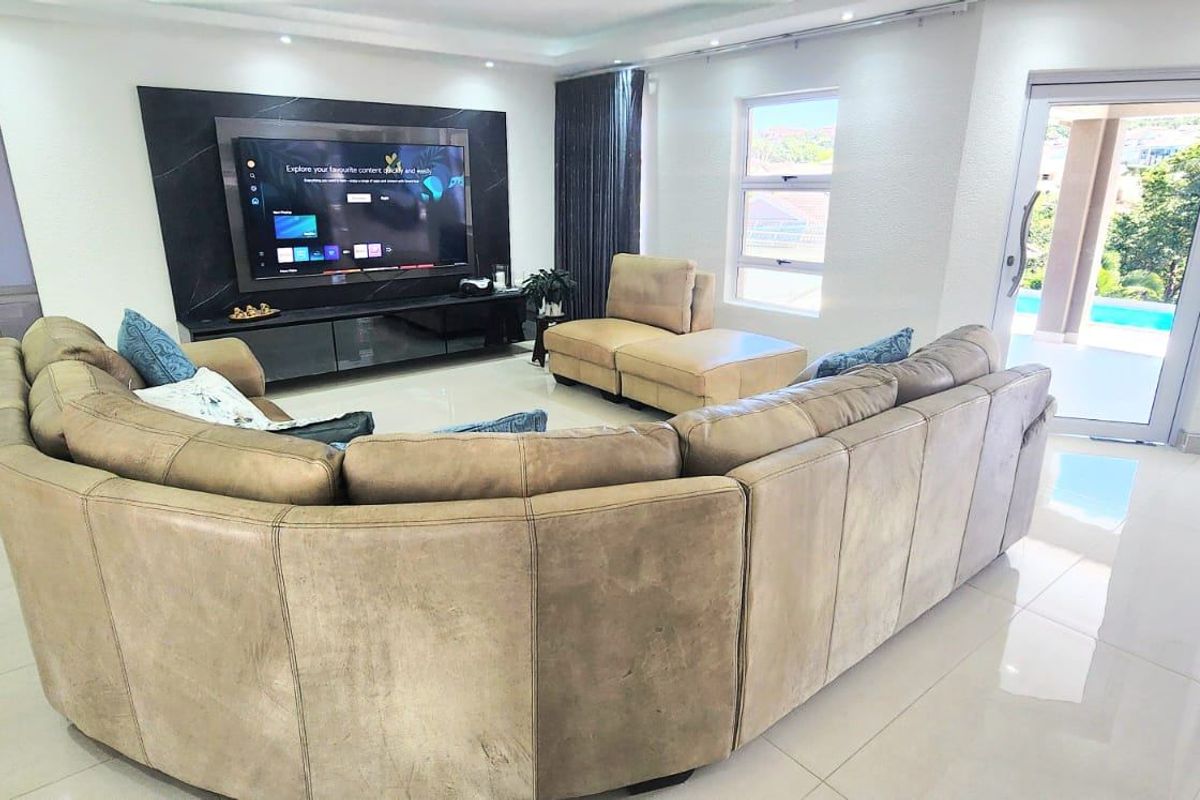 Spacious living room featuring polished porcelain floor tiles, a modern built-in media wall, and direct access to the outdoor pool area via sliding glass doors.