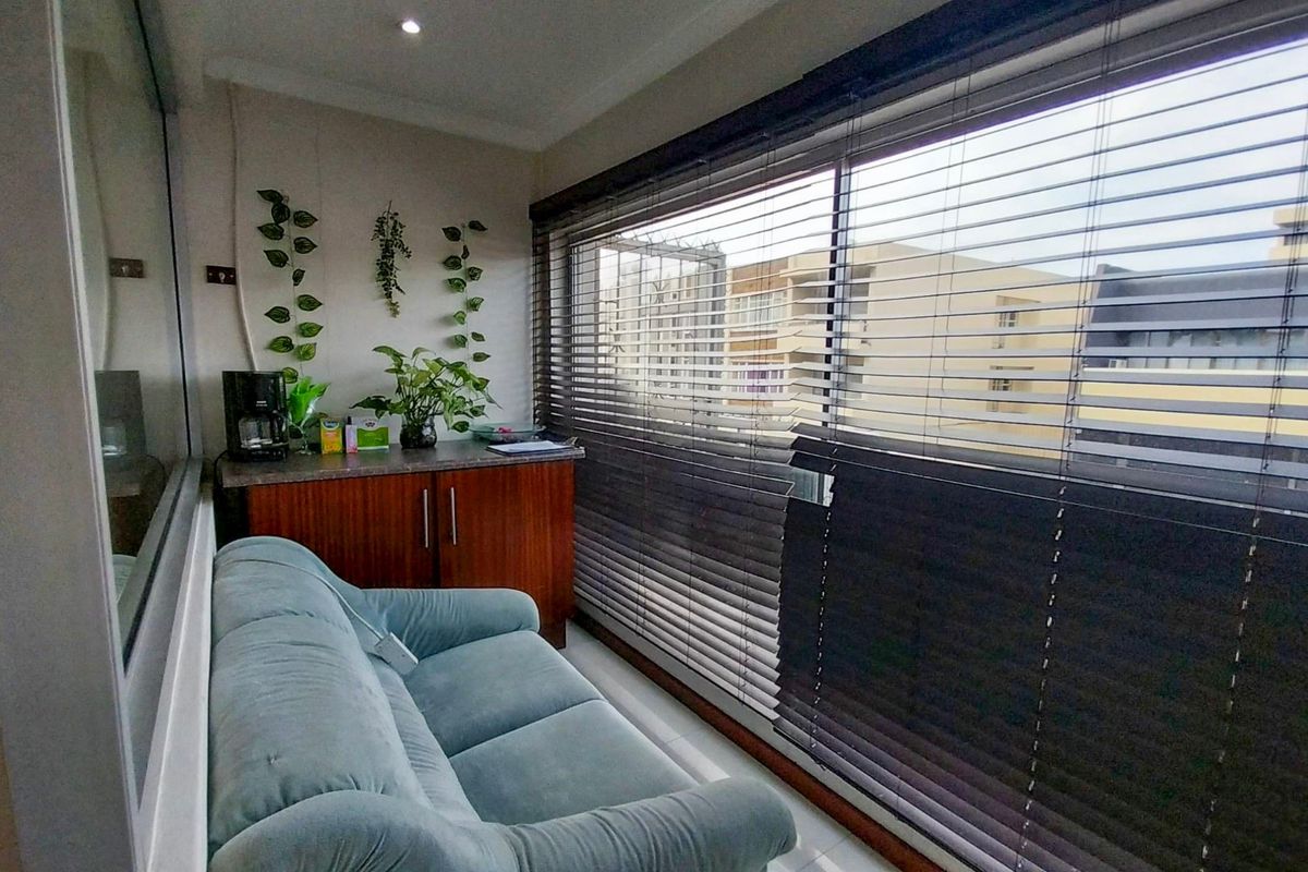 A compact living area featuring built-in cabinetry, large sliding glass doors with venetian blinds, and recessed ceiling lighting.