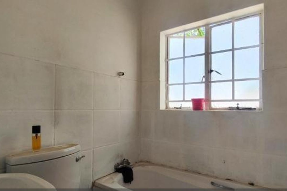 A functional bathroom featuring a bathtub, toilet, and tiled walls, requiring cosmetic updates to improve its overall condition and aesthetic appeal.