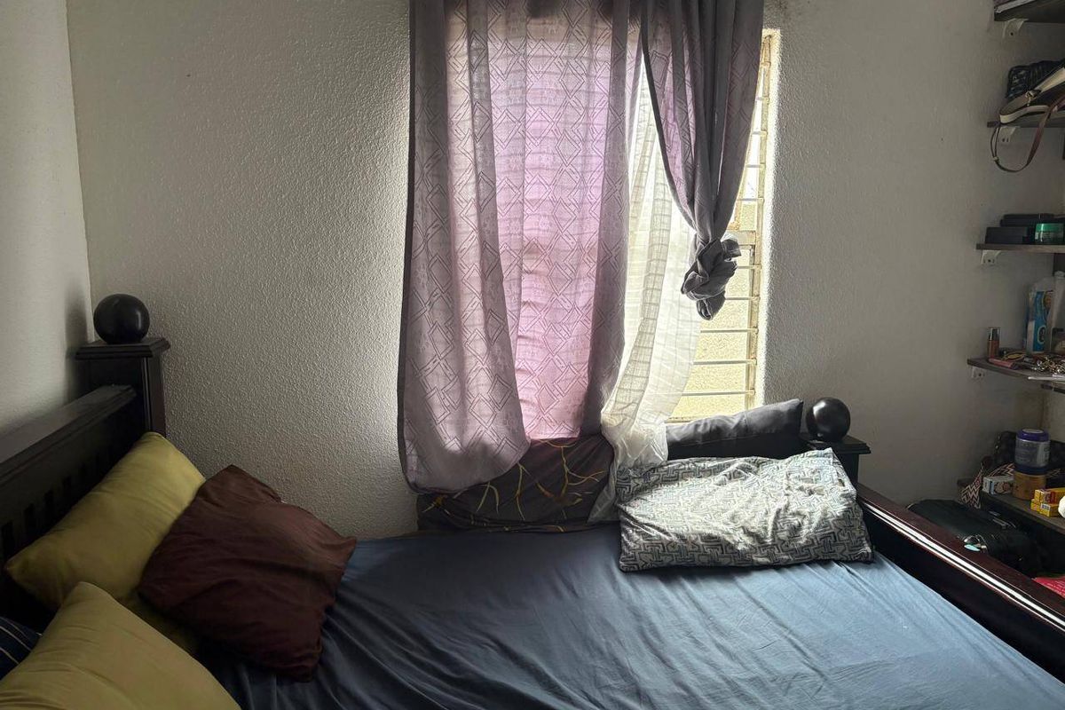 A bedroom featuring a window with security bars, requiring cosmetic updates to the wall finishes.