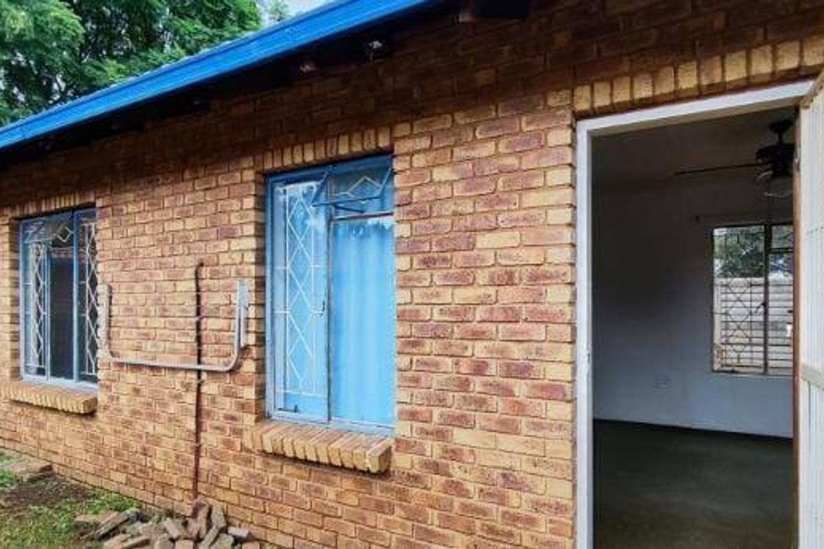 Exterior view of a face brick residential building featuring security gates and metal window frames with security bars.