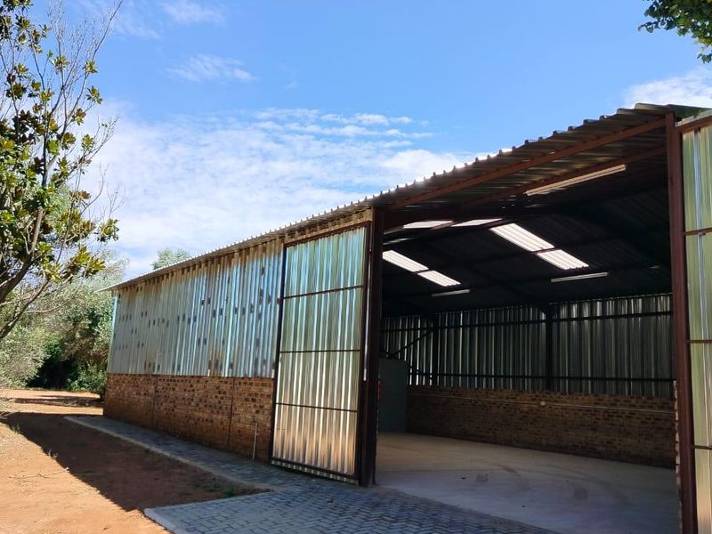 Spacious industrial utility shed featuring corrugated metal walls, a brick base, concrete flooring, and integrated skylights for natural illumination.