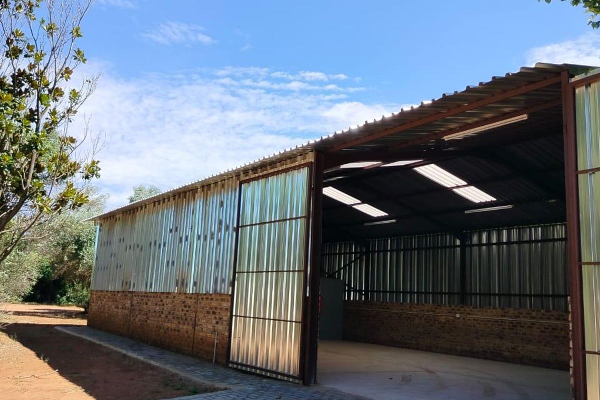 Spacious industrial utility shed featuring corrugated metal walls, a brick base, concrete flooring, and integrated skylights for natural illumination.