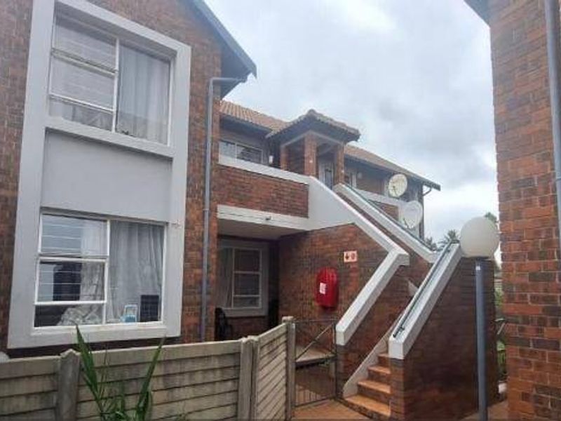 Exterior view of a face brick apartment building featuring an external staircase, metal handrails, and functional fire safety equipment.