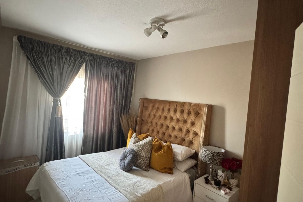 A cozy bedroom featuring tiled flooring and a central ceiling-mounted spotlight fixture, providing a functional and comfortable living space.