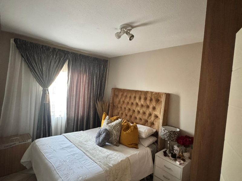 A cozy bedroom featuring tiled flooring and a central ceiling-mounted spotlight fixture, providing a functional and comfortable living space.