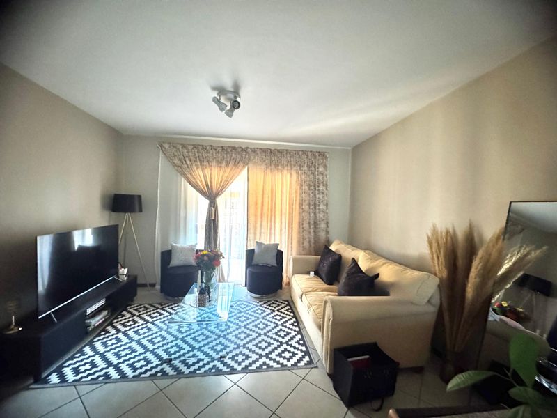 A comfortable living room featuring tiled flooring and a sliding glass door that provides access to the outdoor area.