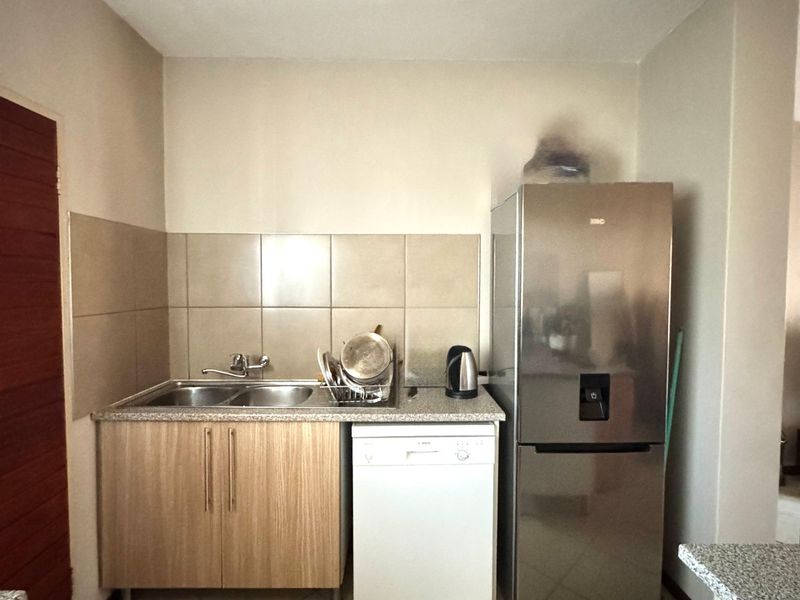 Compact kitchen area featuring laminate cabinetry, granite countertops, a double sink, and tiled backsplash, providing a functional workspace.