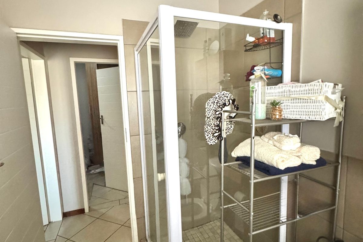 A functional bathroom featuring a corner shower enclosure with tiled walls and flooring, providing a clean and practical layout.