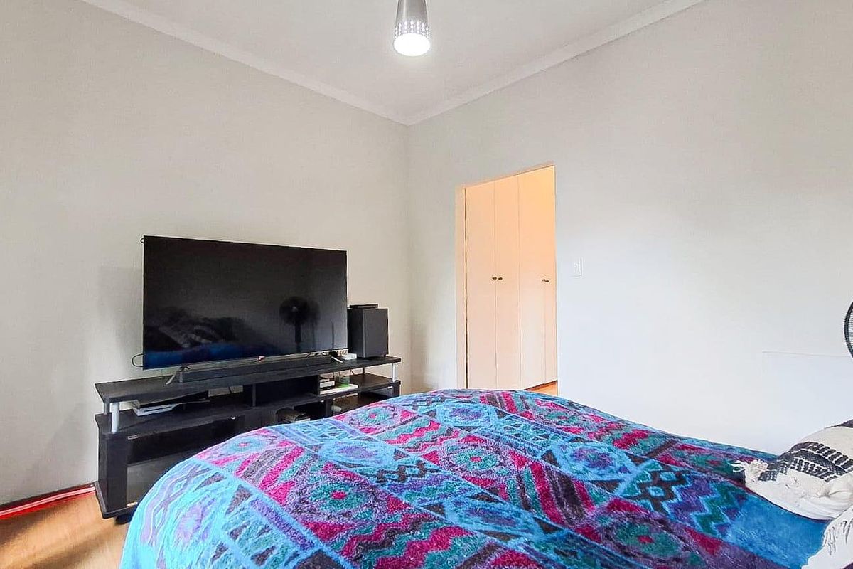 A bedroom featuring laminate flooring, built-in cupboards, and neutral wall finishes.