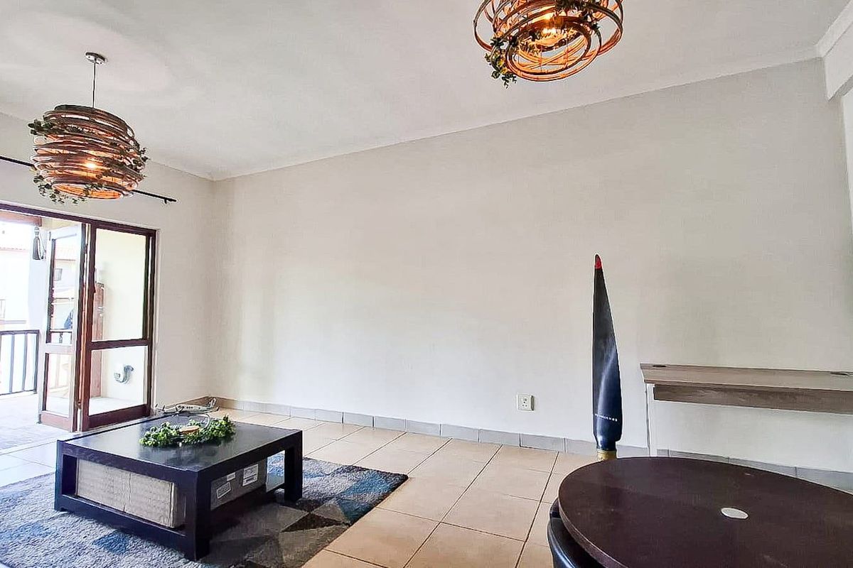 A living room featuring tiled flooring and a sliding glass door leading to an outdoor balcony area.