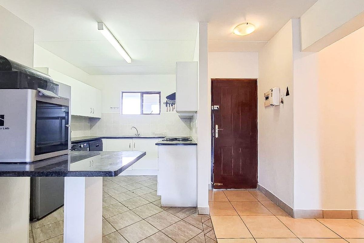Functional kitchen area featuring built-in cabinetry, laminate countertops, and tiled flooring, providing a practical layout for daily meal preparation.