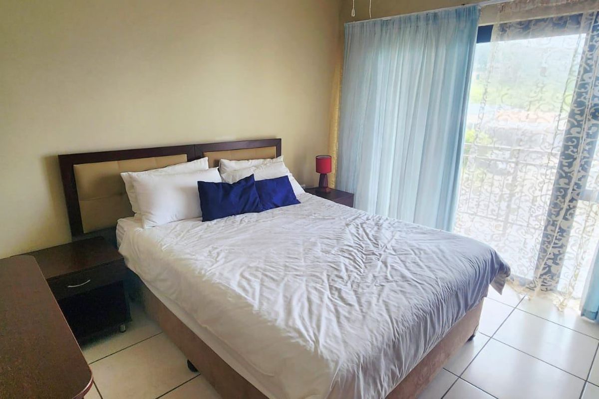 A functional bedroom featuring tiled flooring and a large sliding glass door providing natural light and access to the exterior.