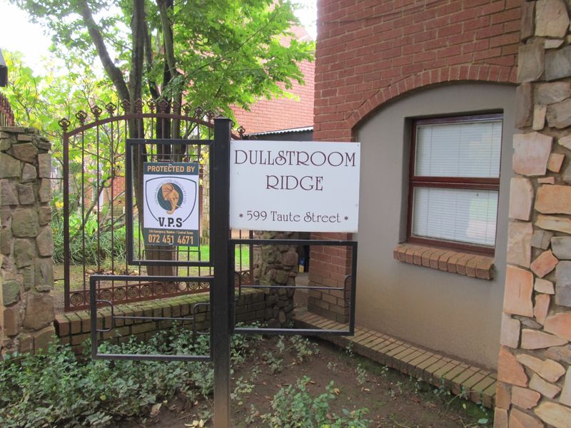 Front entrance area of Dullstroom Ridge featuring brick and stone masonry with a secure wrought iron gate and property signage.