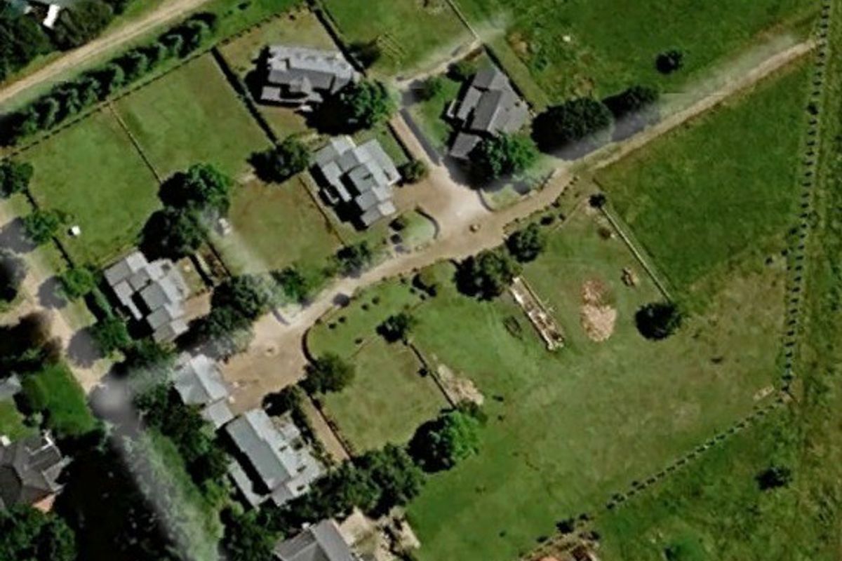 An aerial view of a residential estate featuring multiple dwellings, established green spaces, and internal road infrastructure.