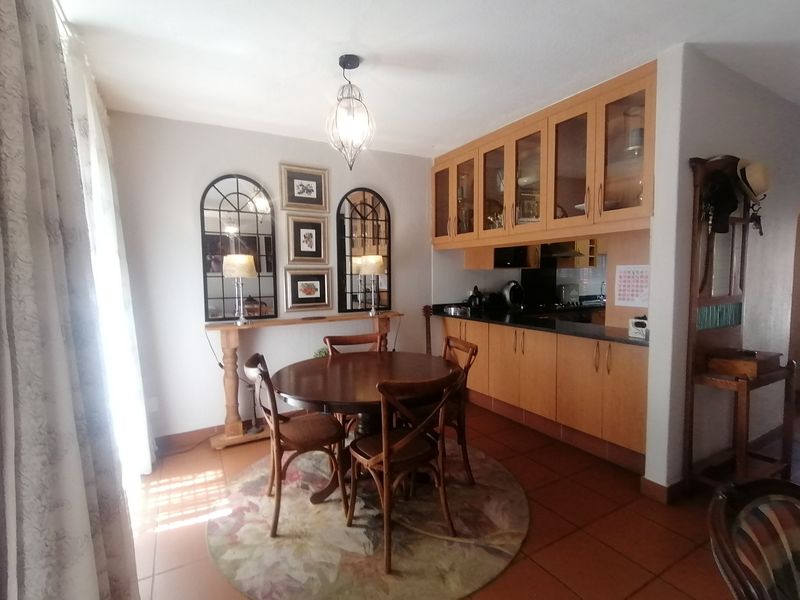 Open plan dining area featuring tiled floors and a functional kitchen with wooden cabinetry and black granite countertops.