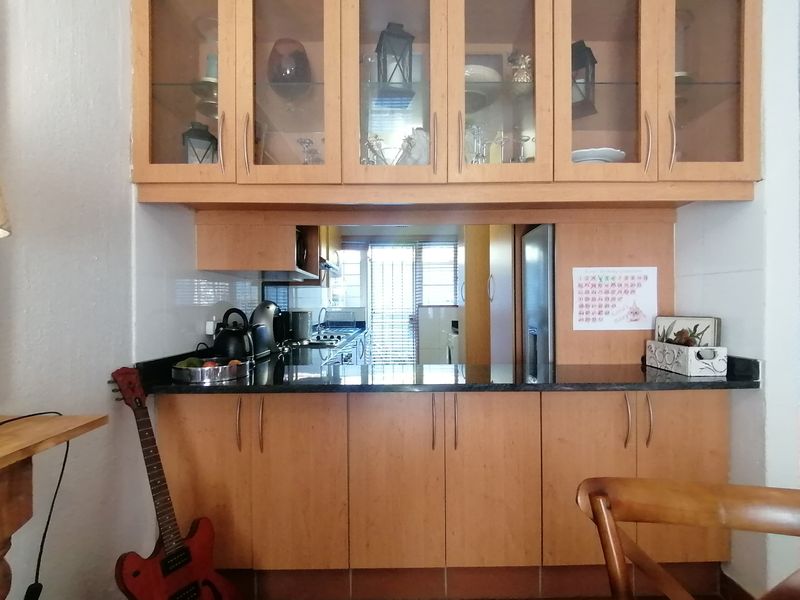 A functional kitchen area featuring light wood cabinetry, granite countertops, and glass-fronted display units, providing ample storage and workspace.