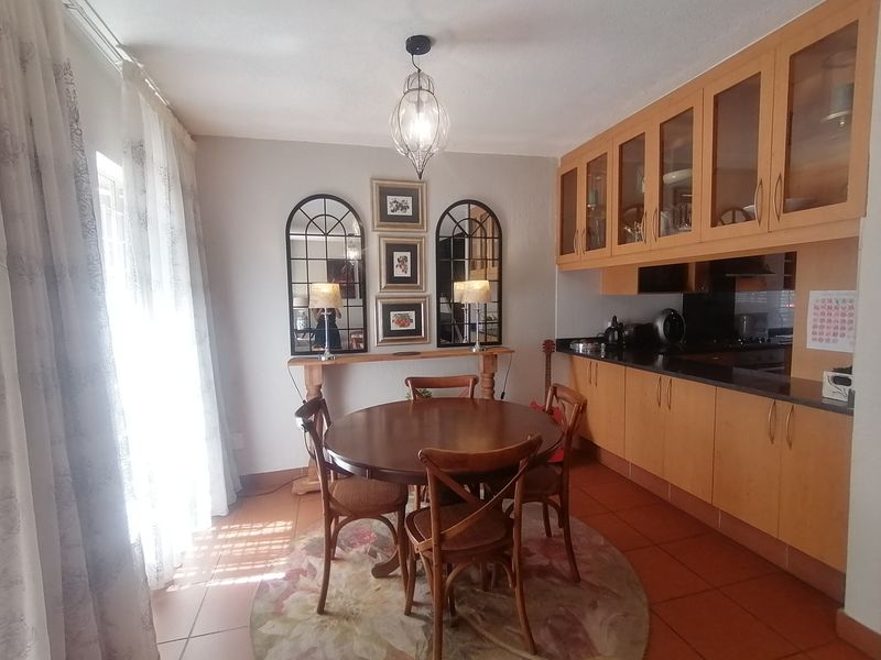 Open plan kitchen and dining area featuring wooden cabinetry, granite countertops, and tiled flooring, offering a functional and well-lit space.