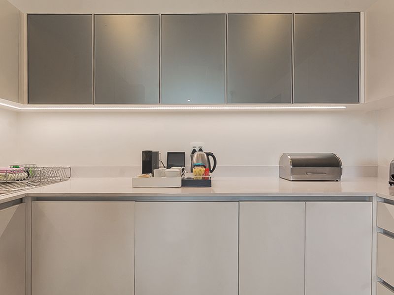 Modern kitchen featuring sleek handleless cabinetry, stone countertops, and integrated under-cabinet LED lighting for a clean, contemporary aesthetic.