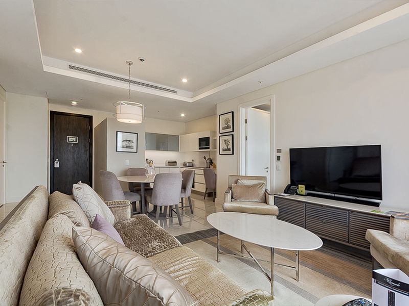 Modern open-plan living area featuring a sleek kitchen, dining space, and lounge with recessed ceiling lighting and high-quality tiled flooring throughout.