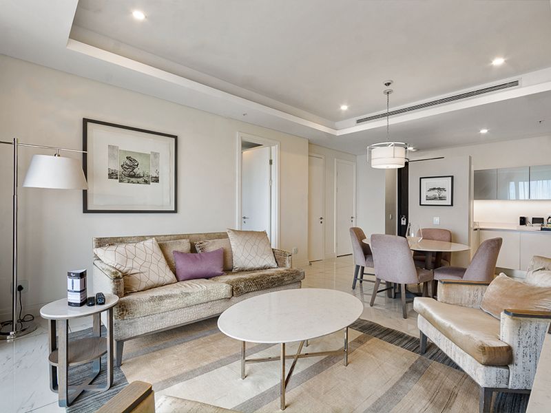 A modern open-plan living and dining area featuring marble flooring, recessed ceiling lighting, ducted air conditioning, and a sleek integrated kitchen.