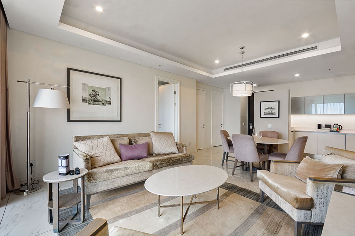 A modern open-plan living and dining area featuring marble flooring, recessed ceiling lighting, ducted air conditioning, and a sleek integrated kitchen.