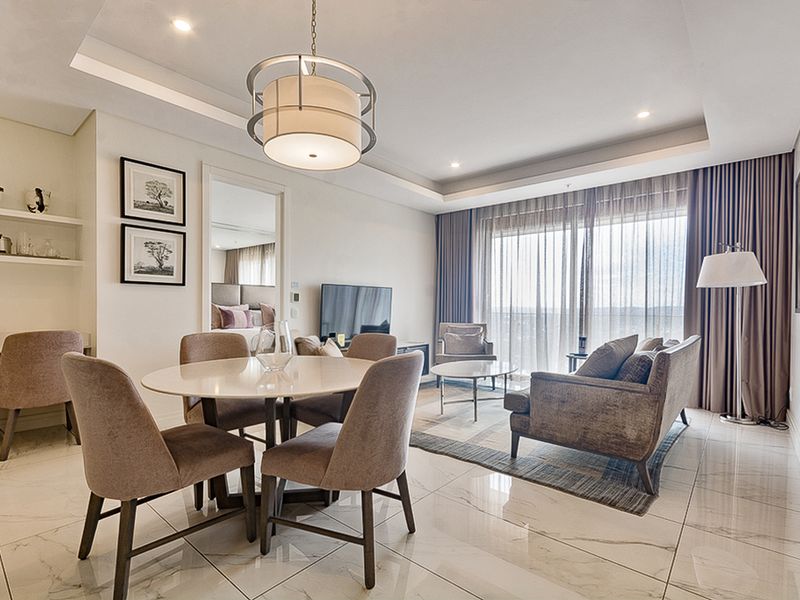 Modern open-plan living and dining area featuring high-quality marble-look floor tiles, recessed ceiling lighting, and large sliding doors leading to a balcony.