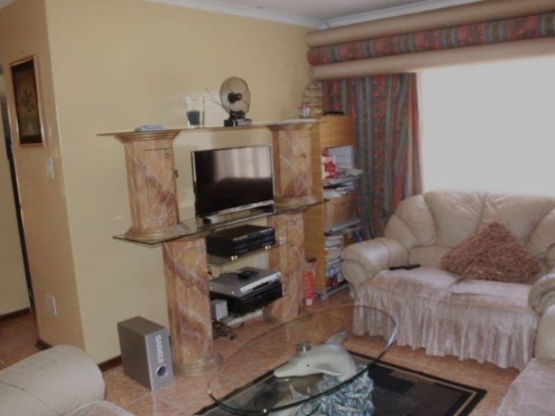 A living room area featuring tiled flooring and decorative cornicing, offering a functional space for relaxation.