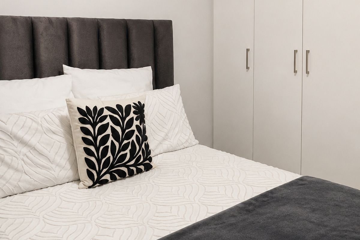 A well-maintained bedroom featuring neutral walls, clean finishes, and integrated floor-to-ceiling built-in wardrobes for efficient storage.