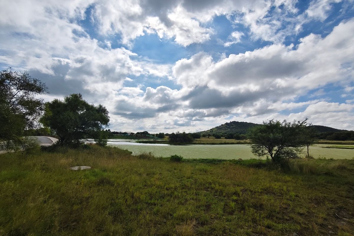 A scenic view of a natural pond and surrounding grassland landscape under a cloudy sky, showcasing the property's natural environment.